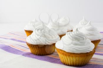 White cupcakes on the striped  linen napkin close up. Homemade cupcakes with whipped cream.  Birthday cupcake. 