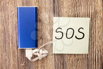 SOS handwritten word on white paper above retro wooden bark background. Concept with help sos sign on the white paper. Save our souls handwritten sign on the white paper.