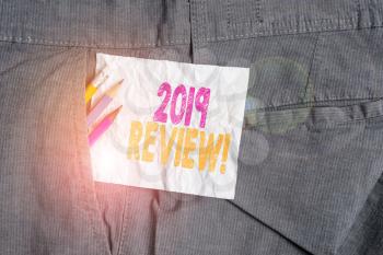 Text sign showing 2019 Review. Business photo showcasing remembering past year events main actions or good shows Writing equipment and white note paper inside pocket of man work trousers