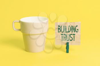 Text sign showing Building Trust. Business photo showcasing activity of emerging trust between showing to work effectively Cup empty paper blue clothespin rectangle shaped reminder yellow office