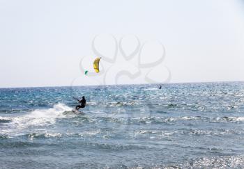 Active man Kitesurfing on the beach with kite. Extreme water sports. Summer vacation leisure time. Kiteboarding. Professional Kite-surfer in action on wave