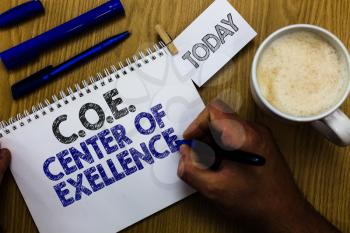Text sign showing C.O.E Center Of Excellence. Conceptual photo being alpha leader in your position Achieve Man holding marker notebook clothespin reminder wooden table cup coffee