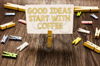 Text sign showing Good Ideas Start With Coffee. Conceptual photo caffeine lovers start day with it to do more Clothespin holding white paper note several clothespins wooden floor