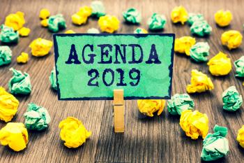 Text sign showing Agenda 2019. Conceptual photo list of activities in order which they are to be taken up Clothespin holding green note paper crumpled papers several tries mistakes