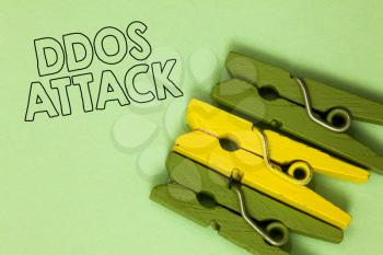 Text sign showing Ddos Attack. Conceptual photo perpetrator seeks to make network resource unavailable Three green yellow vintage clothespins clear background Holding things