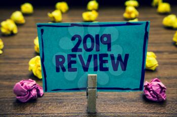 Text sign showing 2019 Review. Conceptual photo seeing important events or actions that made previous year Clothespin holding blue paper note crumpled papers several tries mistakes