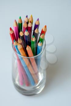 A group of coloured pencils in a glass tumbler