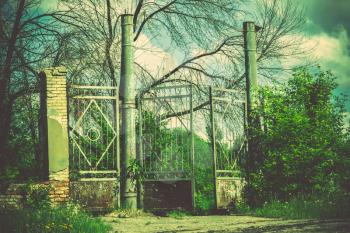 Abandoned rural stadium metal gate and green foliage, filtered background.