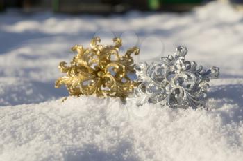 Ornamental golden and silver snowflake glittering on fresh white snow.
