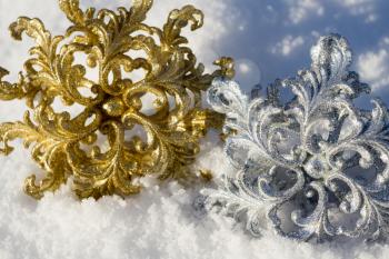 Ornamental golden and silver snowflake glittering on fresh white snow.