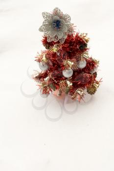 Small red Christmas tree on white snow background.