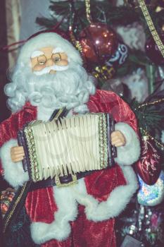 Christmas santa toy playing the accordion, vintage photo effect background.