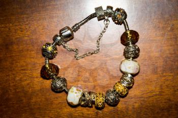 Fashion bracelet with decorative silver and gold charms background.