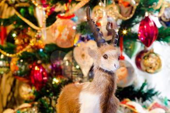 Cute fur ram toy on background with Christmas decorations.