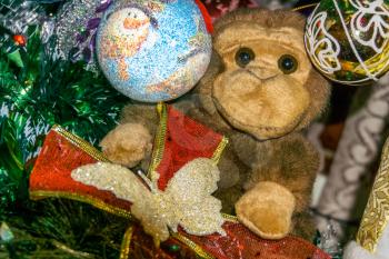Brown monkey toy with decorated Christmas tree. 