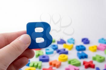 Letter B in hand beside colorful alphabet letter blocks scattered randomly