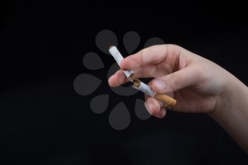 Hand is breaking a cigarette on a black background
