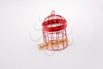 Note about school placed in a red color bird house cage with metal bars