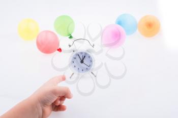 Hand pointing an alarm clock  with balloons on the white background