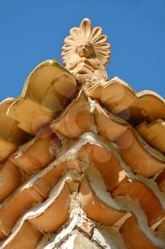 Ceramic antefix decorative ornament on the rooftop of a house in Greece. Architectural detail.