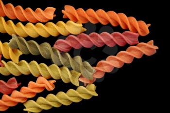 Multi colored fusilli twirls pasta against a black backgrround.