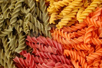 Four different flavors of twirls pasta. Italian food background detail.