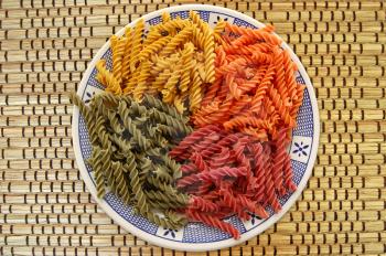 Plate with four flavors of fusilli pasta. Italian food background.