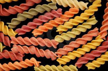 Different flavors of fusilli twists pasta against a black backgrround.