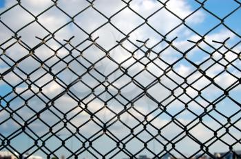 Wire mesh chain link fence pattern against blue sky.