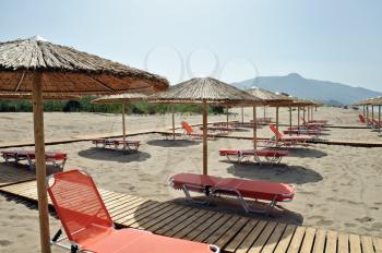 Rows of straw umbrellas and loungers at sandy beach Kalamaki Zakynthos, Greece.