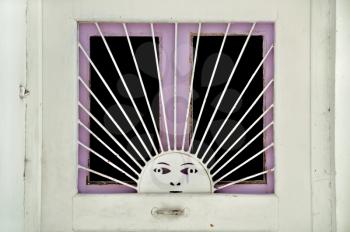 Metal sun pattern on old wooden door window. Vintage metalwork.