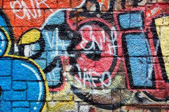 Wall with overlapping layers of messy graffiti and tags. Urban street art background.
