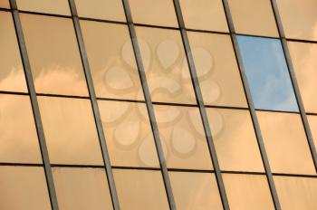 Sky reflected on glass facade panel of a modern building. Abstract background.