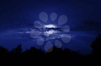 Full moon obscured by clouds. Night sky moonlight nature background.