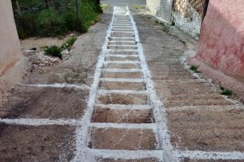 Narrow sloped alley with steps painted white. Greek mountain village old footpath.
