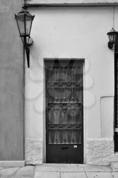 Old door with metal pattern and old fashioned street light. Black and white.