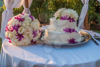 Wedding cake and flowers sit on a table.