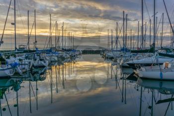 The sun sets behind moored boats  at the Des Moines Marina in Des Moines, Washington.