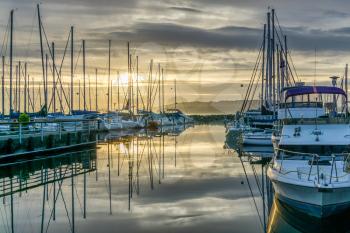 The sun sets behind moored boats  at the Des Moines Marina in Des Moines, Washington.