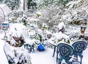 A back yard with garden is covered with snow.