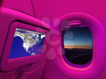 Airplane cabin window with map and sunset