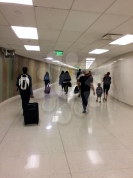 Airport exit tunnel with passengers blurred pulling luggage