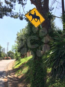 Horse crossing sign yellow with green trees