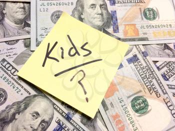 American cash money and yellow post it note with text Kids with question mark in black color aerial view