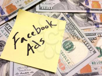 American cash money and yellow paper note with text Facebook Ads in black color aerial view