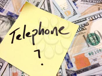 American cash money and yellow sticky note with text Telephone with question mark in black color aerial view