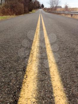 low angle asphalt road double yellow lines no passing lanes countryside perspective