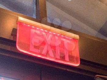 Red exit sign illuminated at emergency exit door indoor
