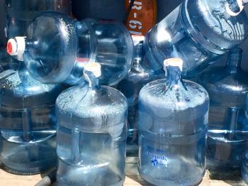 Five 5 gallon water bottles full and empty blue plastic dry and condensation droplets on USS Iowa naval warship destroyer battleship