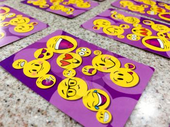 Happy face smiely emoji on playing cards purple color on table